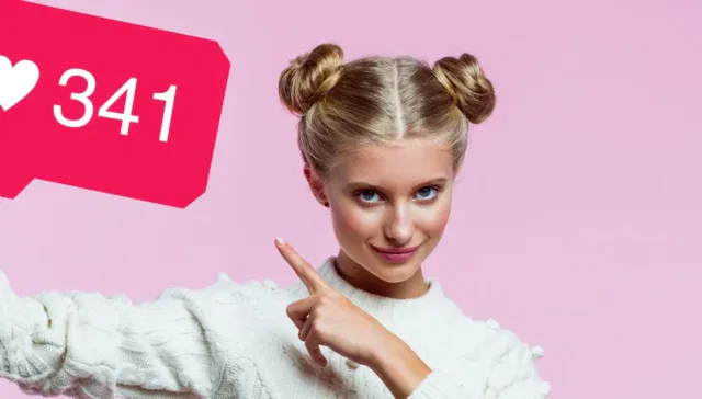 Eine Frau mit blondem Haar in zwei Dutts hält ein großes rosa Instagram-Anzeigenschild mit einem Herz und der Zahl 341 vor einem rosa Hintergrund.
