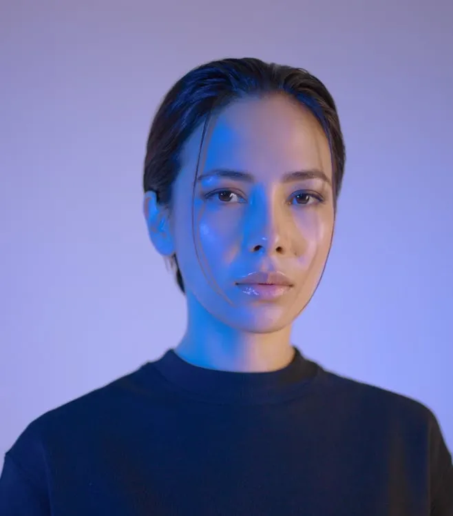Eine Frau in einem schwarzen Hemd mit blauen Lichtern im Gesicht.