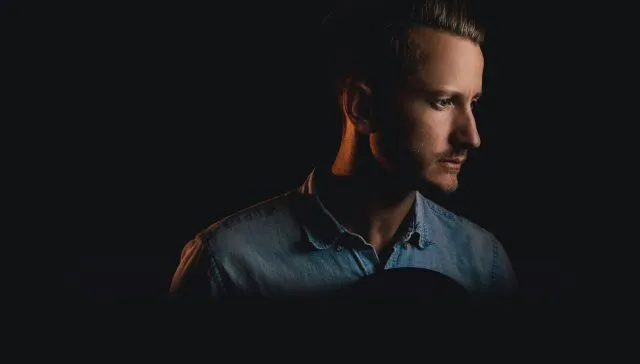 Ein Mann in einem blauen Hemd starrt in die Dunkelheit.