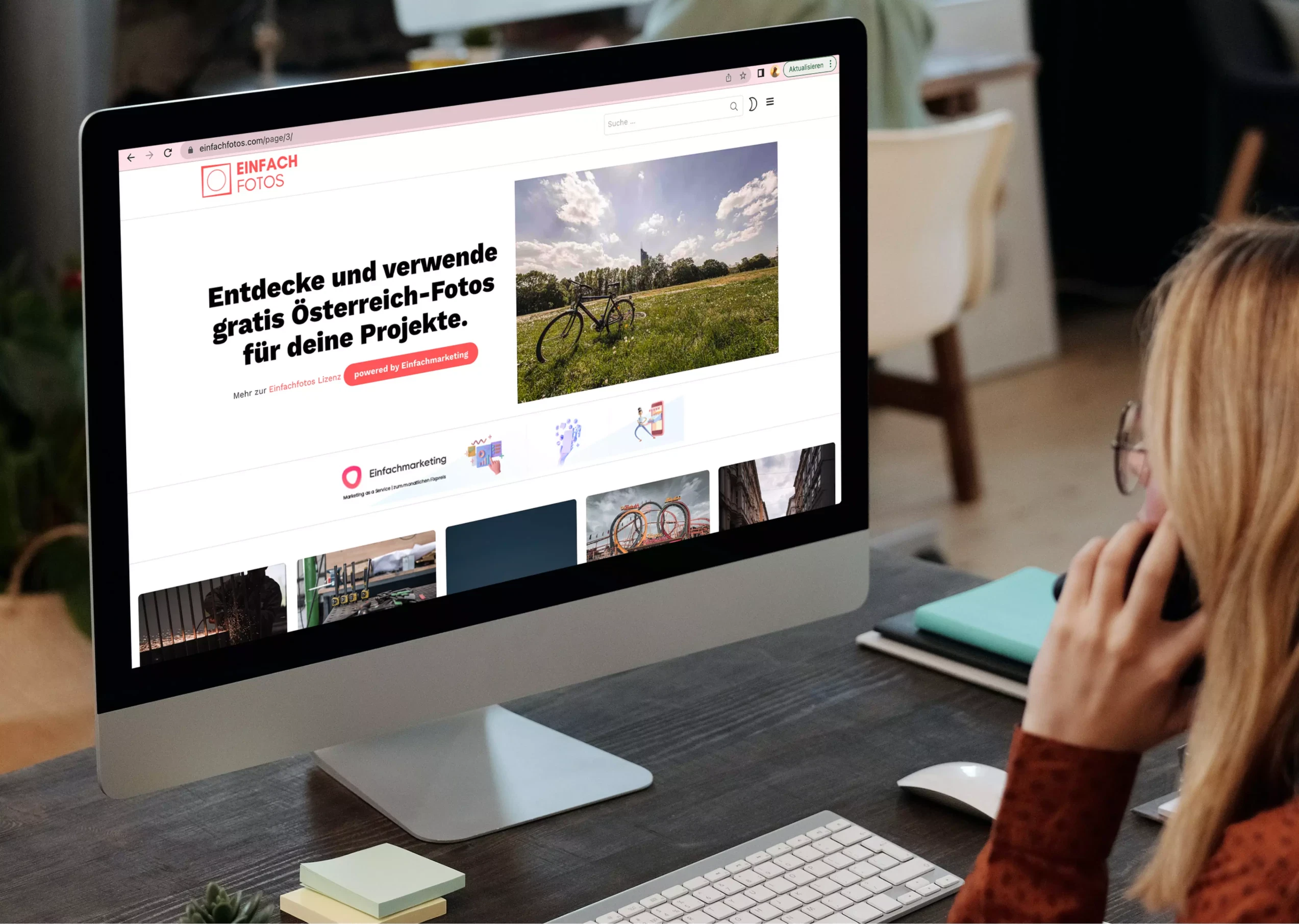 Eine Frau einfachfotos an einem Schreibtisch mit einem Computerbildschirm.