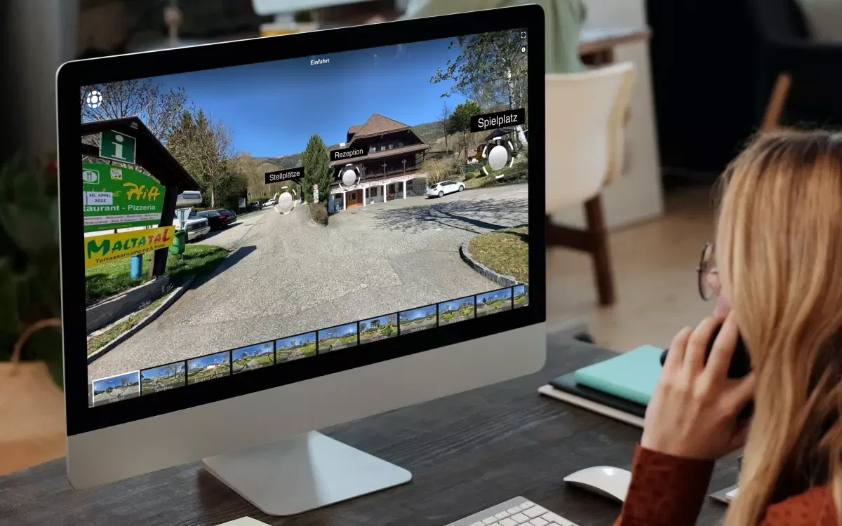 Eine Frau führt während eines Telefonats einen virtuellen Rundgang durch den Campingplatz Maltatal.