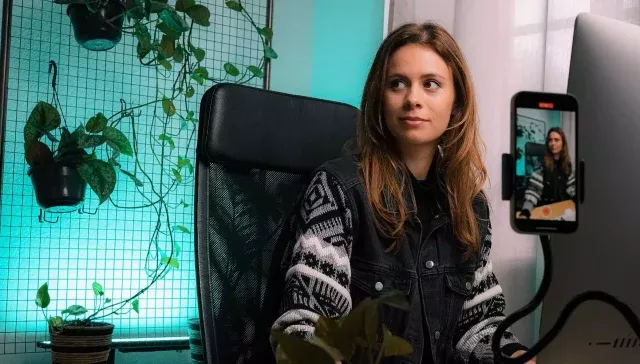 Eine Frau betreibt Content-Marketing, während sie vor einem Computer sitzt und eine Pflanze in der Nähe hat.