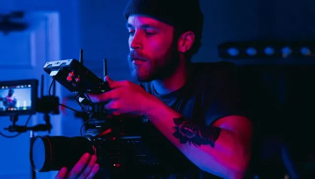 Ein Mann, der zu Marketingzwecken in einem schwach beleuchteten Raum Videomaterial aufnimmt.