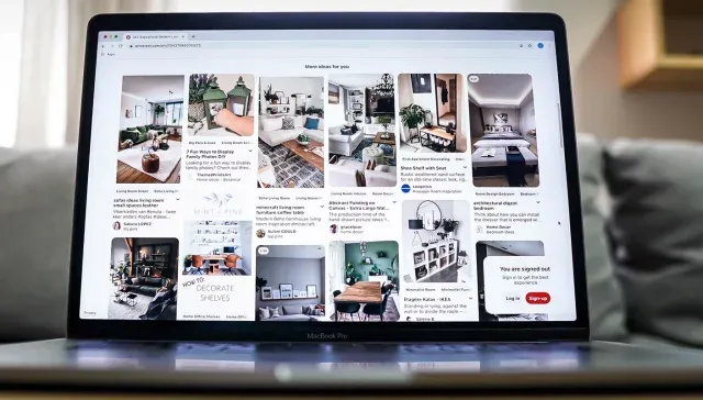 Auf einem Tisch steht ein Laptop mit Bildern, der für Pinterest-Marketing wirbt.