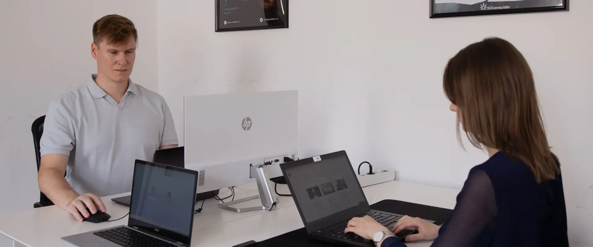 Zwei Personen arbeiten an einem weißen Schreibtisch an Laptops und arbeiten automatisch an einem Projekt zusammen. Jeder von ihnen ist konzentriert und stellt sicher, dass jeder Entwurf und jede gespeicherte Datei perfekt synchronisiert ist, während sie sich zielstrebig gegenüberstehen.